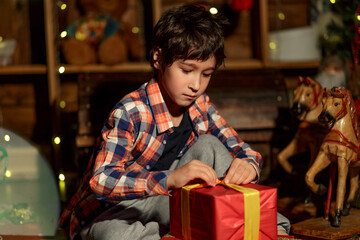 The boy with presents, gifts near Christmas tree. Happy New Year and Merry Christmas. Christmas decorated interior.