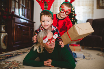 Grandmother and two children are spending time together in the living room. They are having fun for...