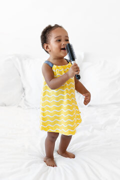 Cute toddler girl singing with hairbrush as a microphone