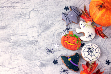 Fototapeta na wymiar Halloween background with cookies, leaves and spiders, top view. Halloween objects on textured concrete with space for text. Vintage background Halloween celebration. Soft focus