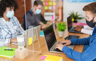 Coworking office and multiracial staff wearing protective face masks for coronavirus - Workplaces and safety measures - Focus on the hand of the man