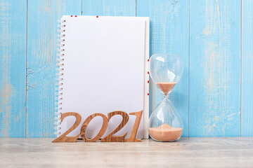 2021 Happy New Year  with blank notebook, Hourglass and wooden number. countdown, New Start, Resolution, Goals, Plan, Action and Mission Concept