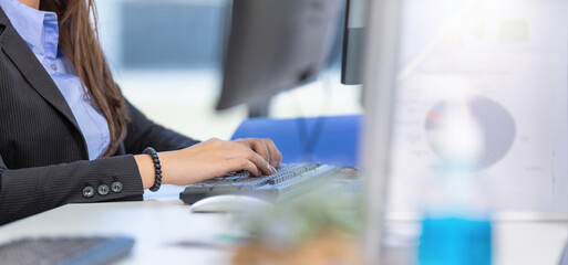 Web banner background of woman employee typing on computer keyboard at working desk in the office....