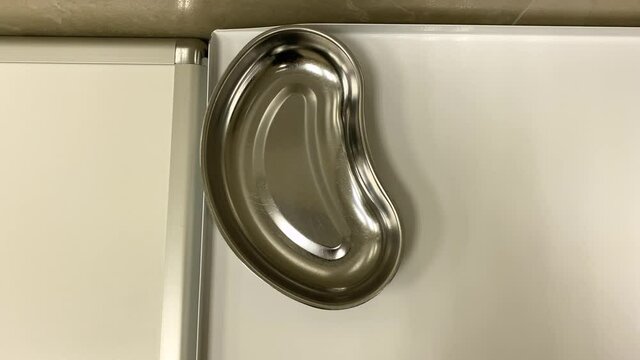 empty clean metal medical bowl for instruments and cotton swabs stands on the table