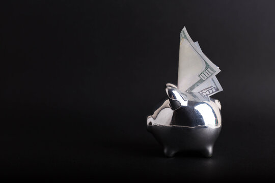 Piggy bank with one hungred dollars on black background. Concept of finance, investment and crisis