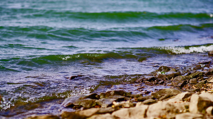 A green wave runs over the shore of sharp stones    