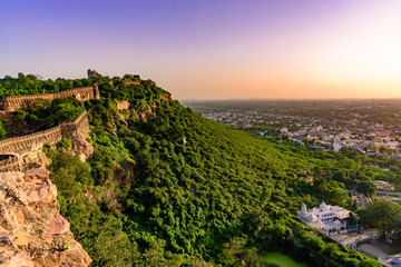 Fototapeta na wymiar View during sunset from Chittor or Chittorgarh Fort with city in backdrop. It is one of the largest forts in India & listed in the UNESCO World Heritage Sites list as Hill Forts of Rajasthan.