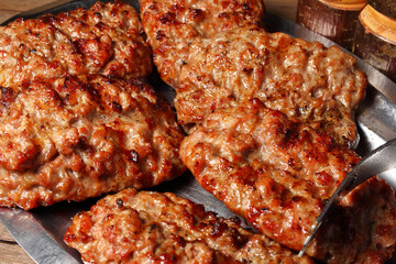 Salsiccia di maiale arrostita sulla brace e disposta su un vassoio di acciaio.