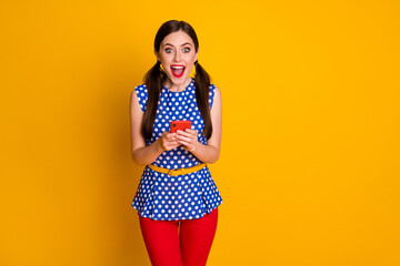 Portrait of astonished positive girl use smartphone impressed social media feedback wear trendy pants isolated over bright shine color background