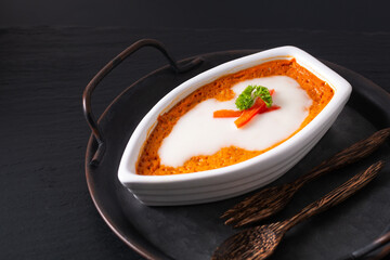 Asian food concept Thai Steamed Curried Fish, Steamed Red Curry Custard Hor Mok in white ceramic boat shape on rustic iron tray on black background