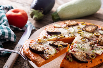 Autumn pumpkin pizza with vegetables on wooden table.	