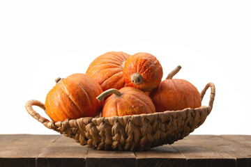Orange round pumpkins in wicker basket on wooden table. Copy space, Halloween design.
