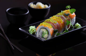 Sushi rolls set served on black plate on dark background.Menu concept.