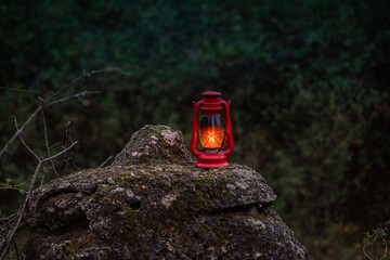 old red petrol lamp on a stone in the middle of the forest. autumn background