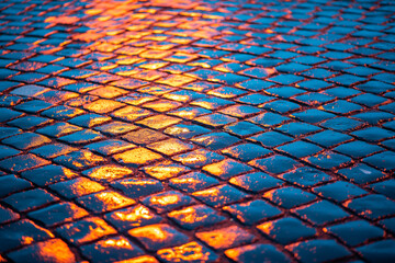 city lights reflected in wet cobblestone at night