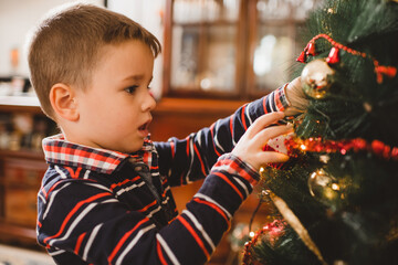 Little boy decorating Christmas tree at home