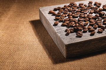 Coffee beans are scattered on a board that is lying on the fabric.