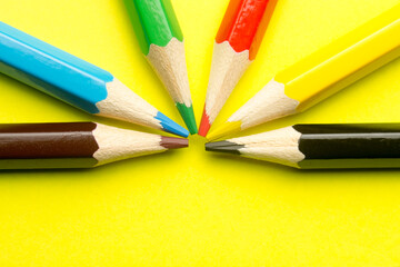 Colored pencils on a yellow background close-up.