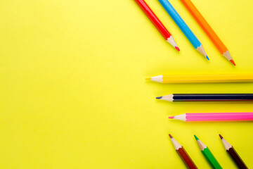 Colored pencils on a yellow background close-up.