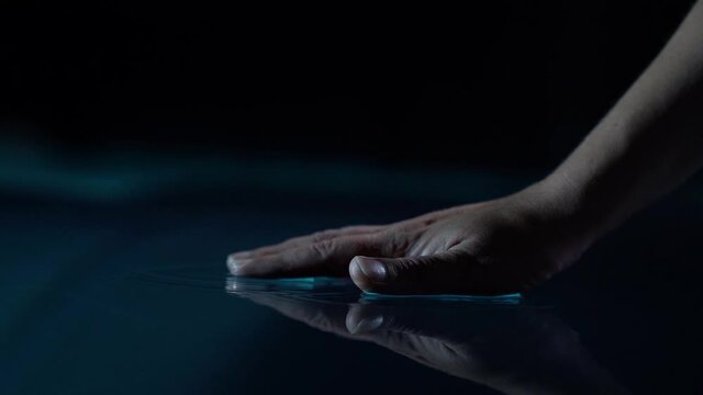 woman is touching surface of water, closeup of hand, gloomy and mystical mood, dark blue water
