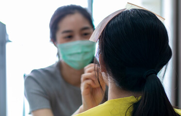Selected focus on Model for makeup. Makeup artist wearing face mask doing makeup for girl indoor...