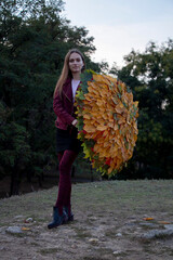 Beautiful girl in the park. Holds an umbrella covered with autumn yellow leaves. Autumn.