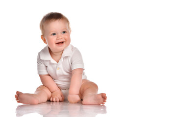 Cute little boy in white bodysuit sitting isolated on white