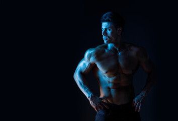 Muscular model sports young man on dark background. Fashion portrait of strong brutal guy. Sexy...