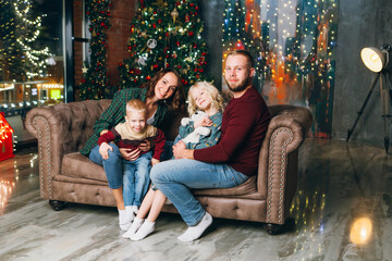 Obraz premium Young family with two children at the Christmas tree