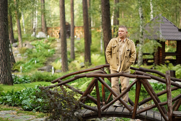  a man walks in the Park,stands on a wooden bridge.