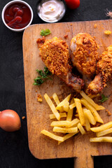 
Delicious homemade crispy fried chicken with sauces on black marble background