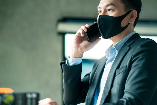 smart attractive asian male businessman wearing face mask virus protecting working with smartphone in cafe new normal working lifestyle business concept