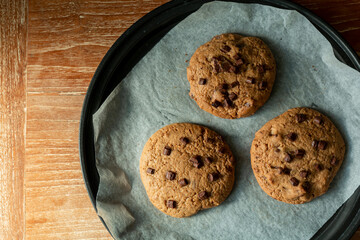 Homemade cookies on cooling tray. Cookies with chocolate on dark wooden background. Homemade Chocolate chip cookies.