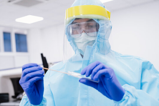 Medical scientist in PPE suit uniform holding swab coronavirus test in laboratory