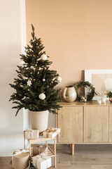 Beautiful Christmas tree with toys, baubles and homemade paper gift boxes. Living room decorated for Christmas / New Year celebration. Modern interior design concept.