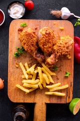 
Delicious homemade crispy fried chicken with sauces on black marble background