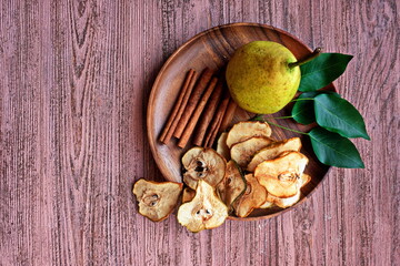  Organic pear chips. Dried fruits. Healthy sweet snack. Dehydrated and raw food. Vegetarian appetizer on a wooden plate. Copy space