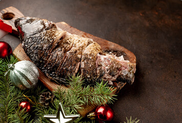 baked carp for the holiday of Christmas on a stone background with Christmas trees and Christmas tree decorations with copy space for your text