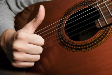 man playing acoustic guitar thumbs up