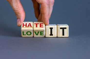 Hand turns cubes and changes the words 'love it' to 'hate it' or vice versa. Beautiful grey background. Business concept, copy space.
