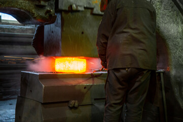 close-up picture of hot steel free forging process with big mechanical hammer machine