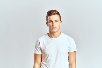Handsome man in a white T-shirt on a light background close-up portrait cropped view