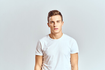 Obraz premium Handsome man in a white T-shirt on a light background close-up portrait cropped view