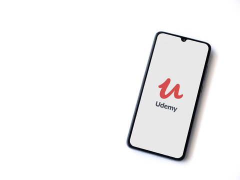 Lod, Israel - July 8, 2020: Udemy app launch screen with logo on the display of a black mobile smartphone isolated on white background. Top view flat lay with copy space.