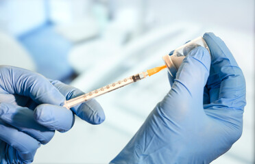 Doctor or nurse holding flu vaccine, measles injection syringe prepare for baby and adult vaccination, medicine and drug concept, hospital background