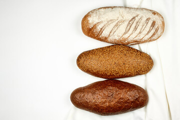 Various kinds of bread on white fabric surface. View from above