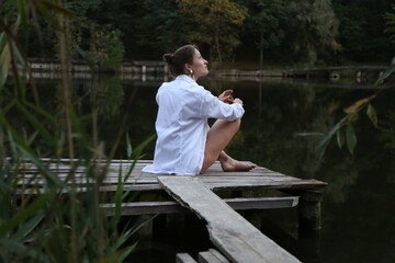 Woman in white shirt sitting near the lake