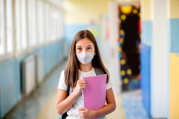 Elementary schoolchild wearing a protective face masks in the school. Education during epidemic.