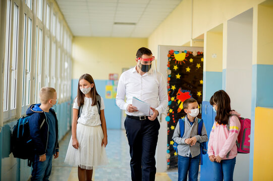 Elementary school students and male teacher wearing protective face masks at school