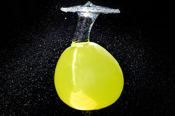 gelber, mit Wasser gefüllter Ballon explodiert